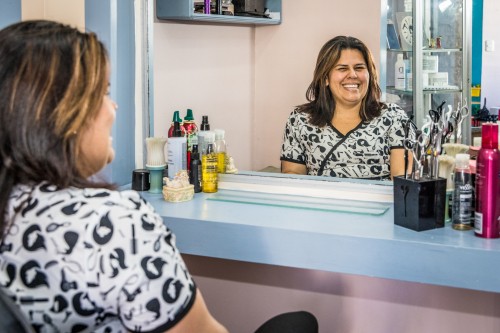 Mujer beneficiaria de microcréditos en su negocio, una peluquería