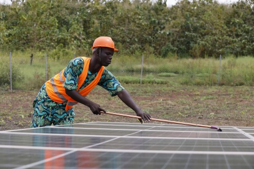 Un operari netejant una 'instal·lació solar fotovoltaica a Àfrica, impulsada per Oikocredit.